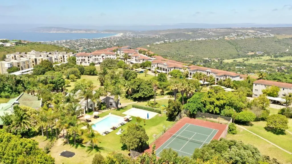 Aerial view of the estate's communal pool, tennis courts and gardens with Plettenberg Bay visible in the distance