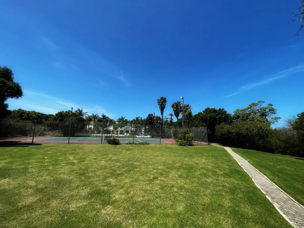 Communal tennis court on the estate bordered by palm trees and open lawns
