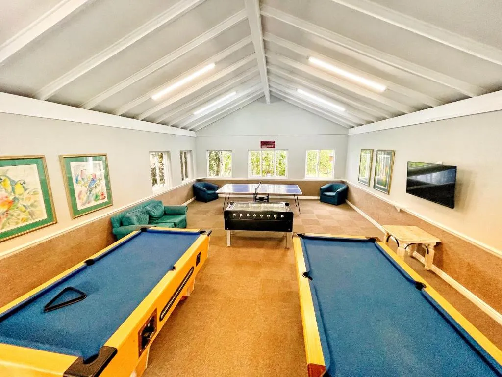 Estate games room with two pool tables, table tennis and foosball under a vaulted ceiling
