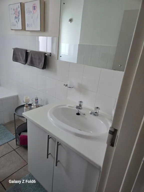 Bathroom with a white vanity, mirrored cabinet and grey towels
