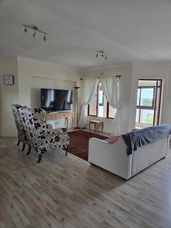 Living room with wingback armchairs, a TV console and windows toward the bay