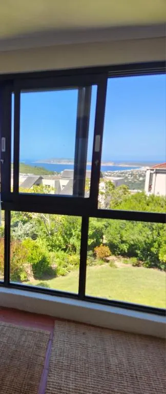 Wide window view over rooftops and garden to the bay and headland beyond
