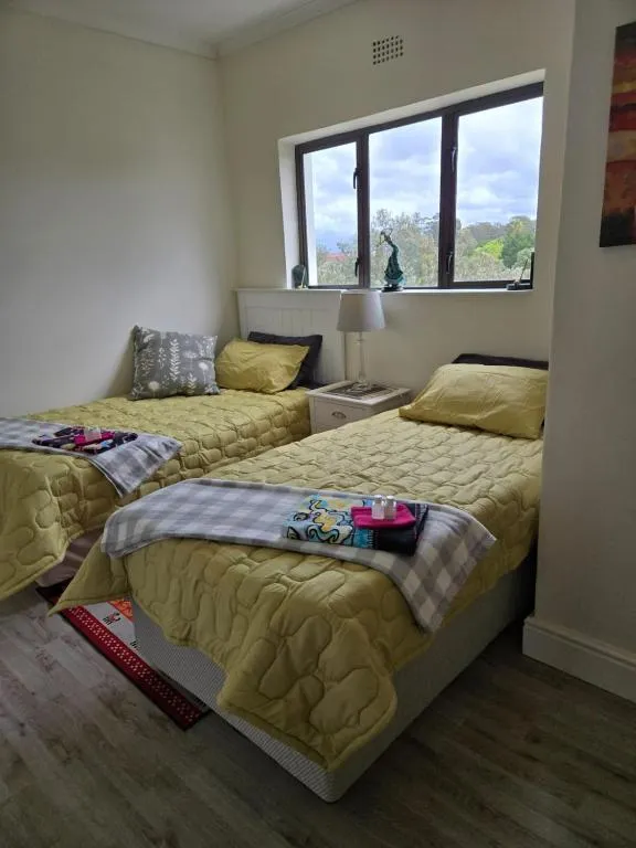 Twin bedroom with mustard bedspreads and a window onto treetops