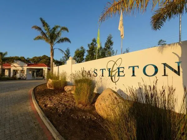 Castleton estate entrance sign framed by palm trees and manicured planting