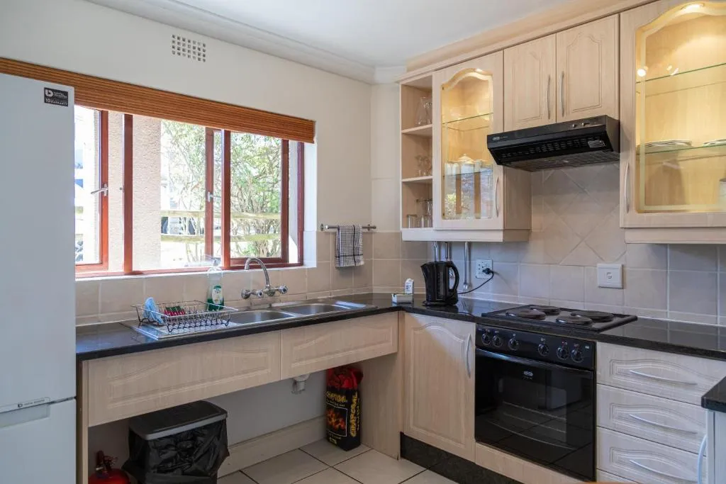 Kitchen with cream cabinetry, a black stove, and a window looking onto greenery