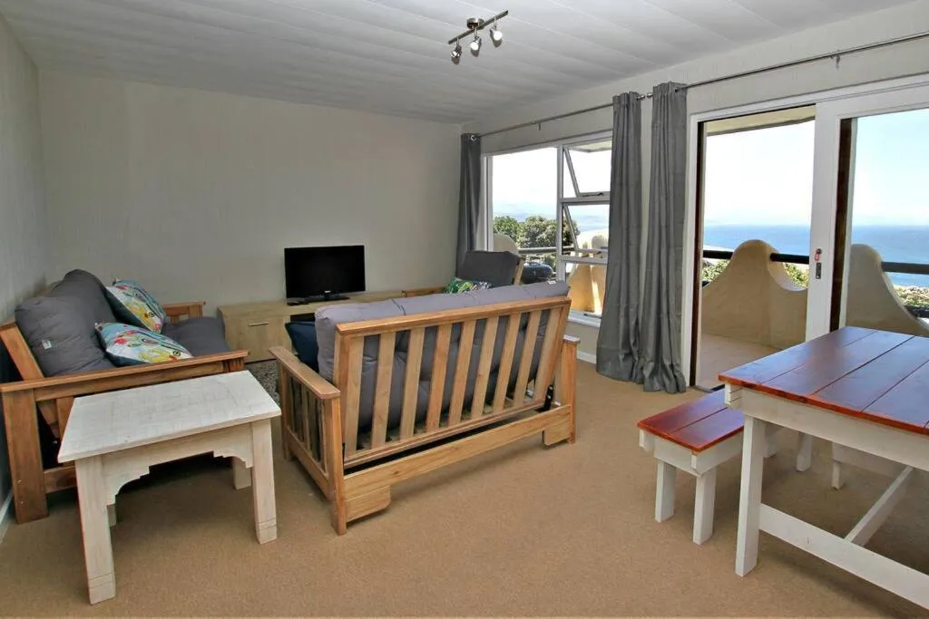 Living and dining area with sliding doors onto a sea-view balcony with curved privacy walls