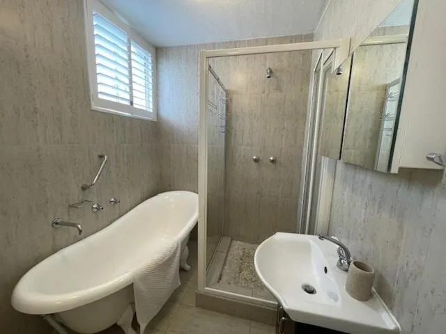 Bathroom with a freestanding claw-foot tub, separate glass shower and pedestal basin