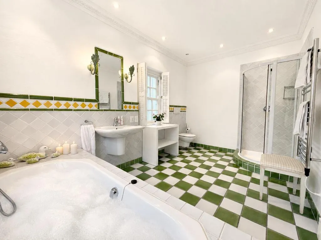 Bathroom with green-and-white tiled floor, freestanding tub and walk-in shower