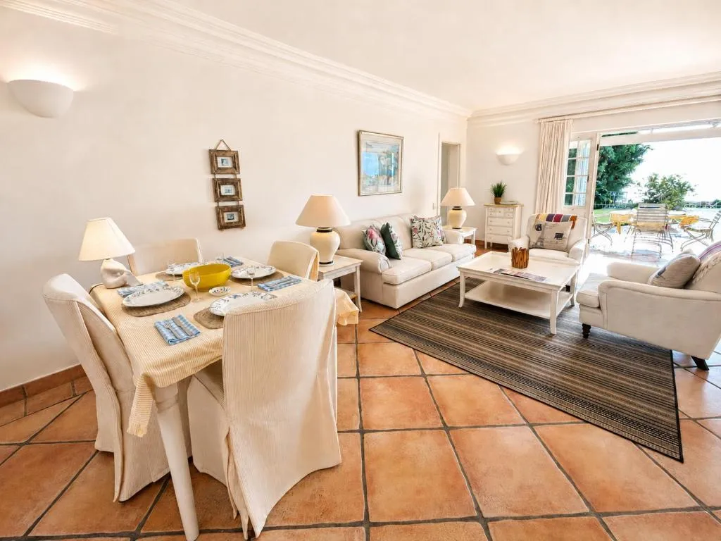 Open-plan lounge and dining area with cream sofas and doors onto the patio