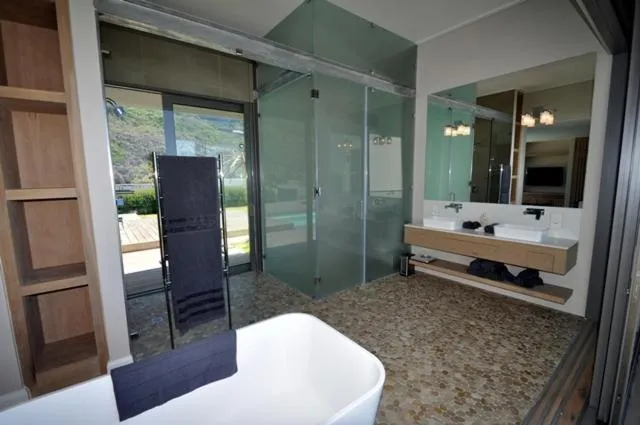 Bathroom with freestanding tub, glass shower and a sea view through the window