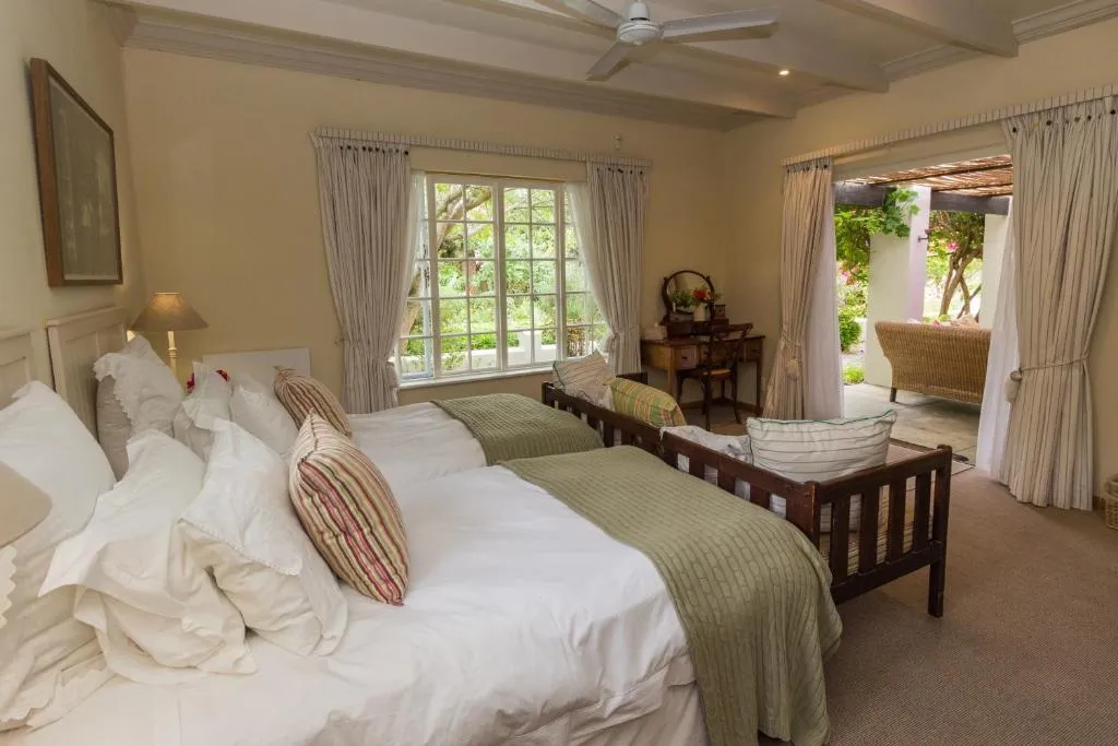 Twin beds pushed together beneath a ceiling fan, with French doors onto a private veranda