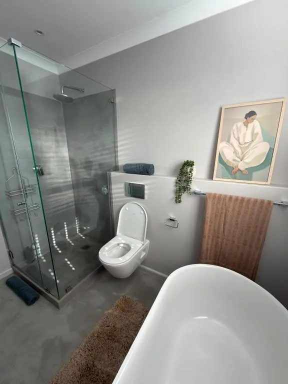 Bathroom with a glass-walled shower, freestanding tub and wall art above the towel rail