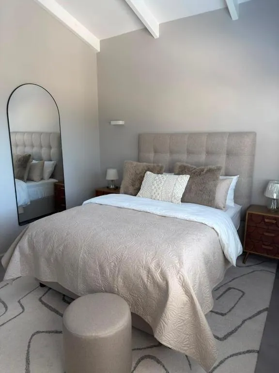 Bedroom with a tufted headboard, faux-fur cushions and a full-length arched mirror