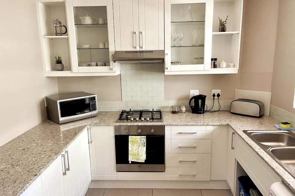 White granite kitchen with a gas hob, built-in oven, microwave and glass-front display cabinets
