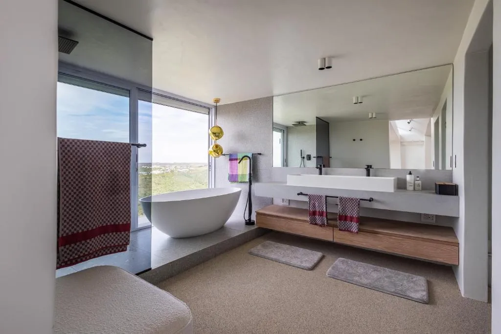 Bathroom with a freestanding tub, walk-in shower and glass doors onto a hillside-view balcony