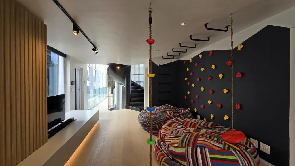 Upper-level games area with a climbing wall, monkey bars and oversized striped bean bags