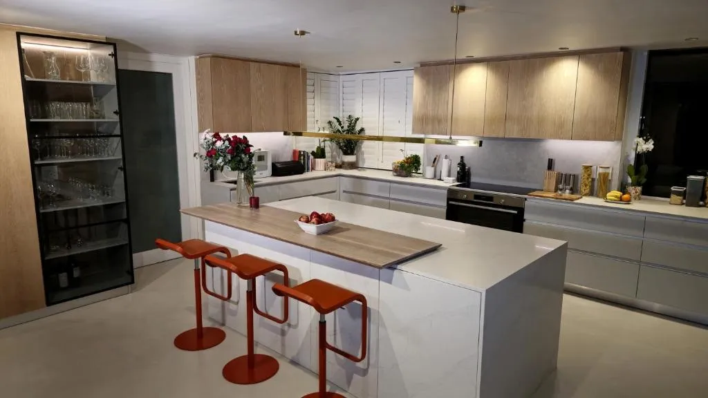 Kitchen with a marble island, glass-fronted wine cabinet and orange bar stools