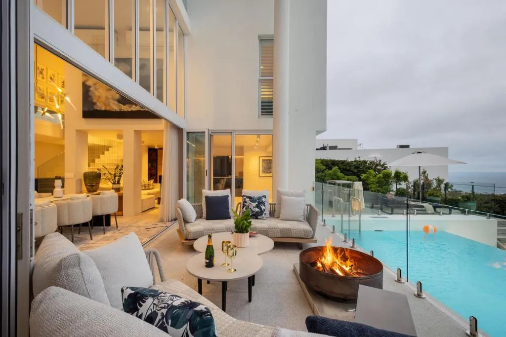Evening terrace lounge with a fire pit beside the infinity pool and open-plan dining behind