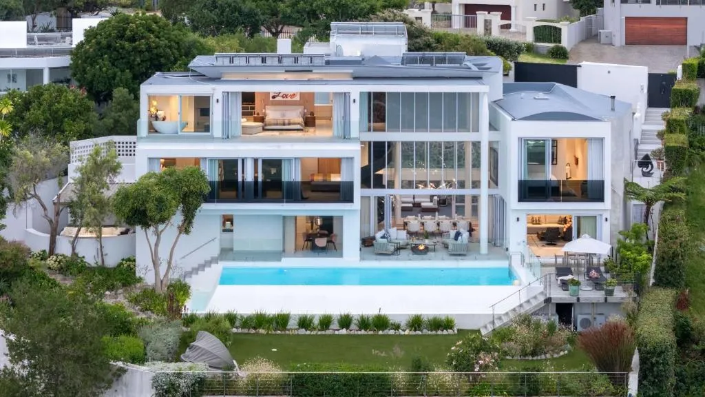 Aerial view of the three-storey glass villa with an infinity pool, terraced garden and pool deck