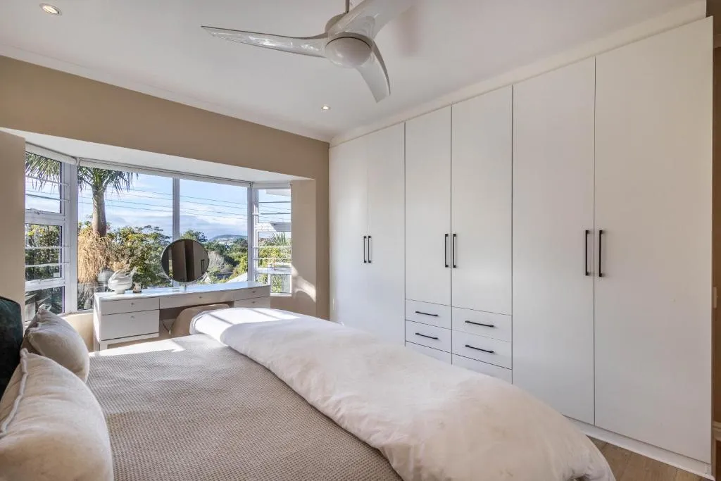 Bedroom with a bay window seat overlooking palm trees and rooftops toward the hills