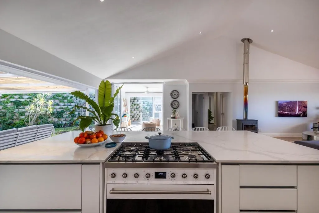 Open-plan kitchen with a marble island, gas range and a wood burner visible beyond
