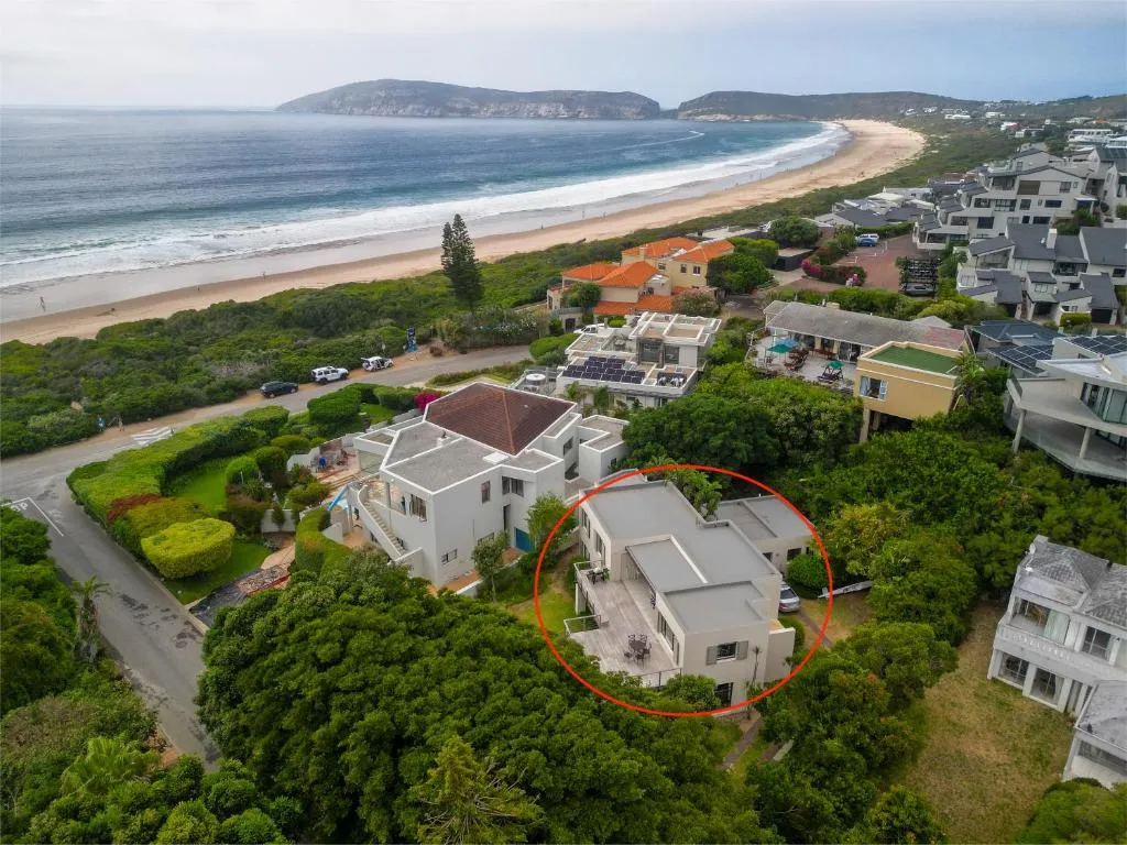 Aerial photo circling the house within a row of beachfront properties above Robberg Beach and the bay
