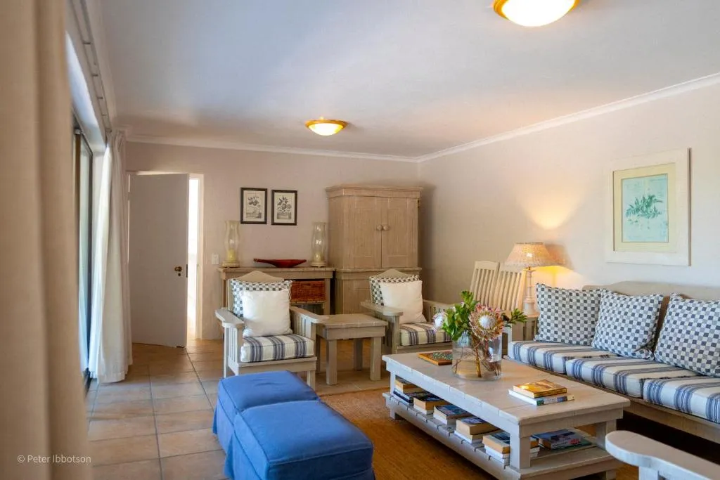 Living room with striped armchairs, a wooden coffee table stacked with books and a blue ottoman