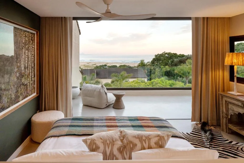 Bedroom with a plaid throw and sliding doors onto a private balcony overlooking the beach