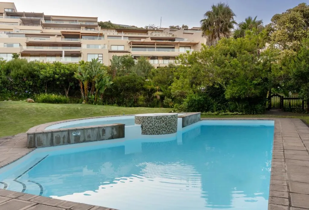 Complex swimming pool set in a landscaped garden below the apartment building