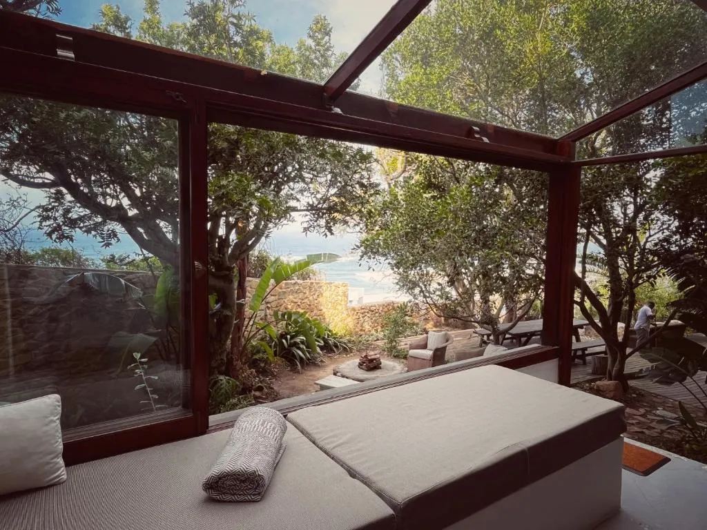 Outdoor deck and glass sunroom looking over a stone garden wall to the sea