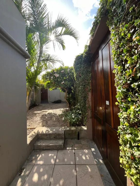 Ivy-covered garden walkway with a wooden gate and stone steps beside the cottage