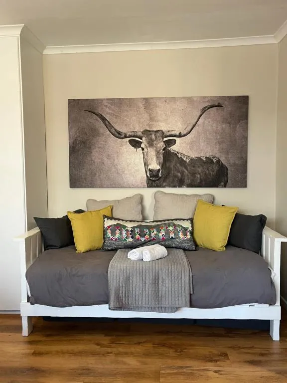 Grey daybed sofa styled with cushions beneath a longhorn cow canvas print