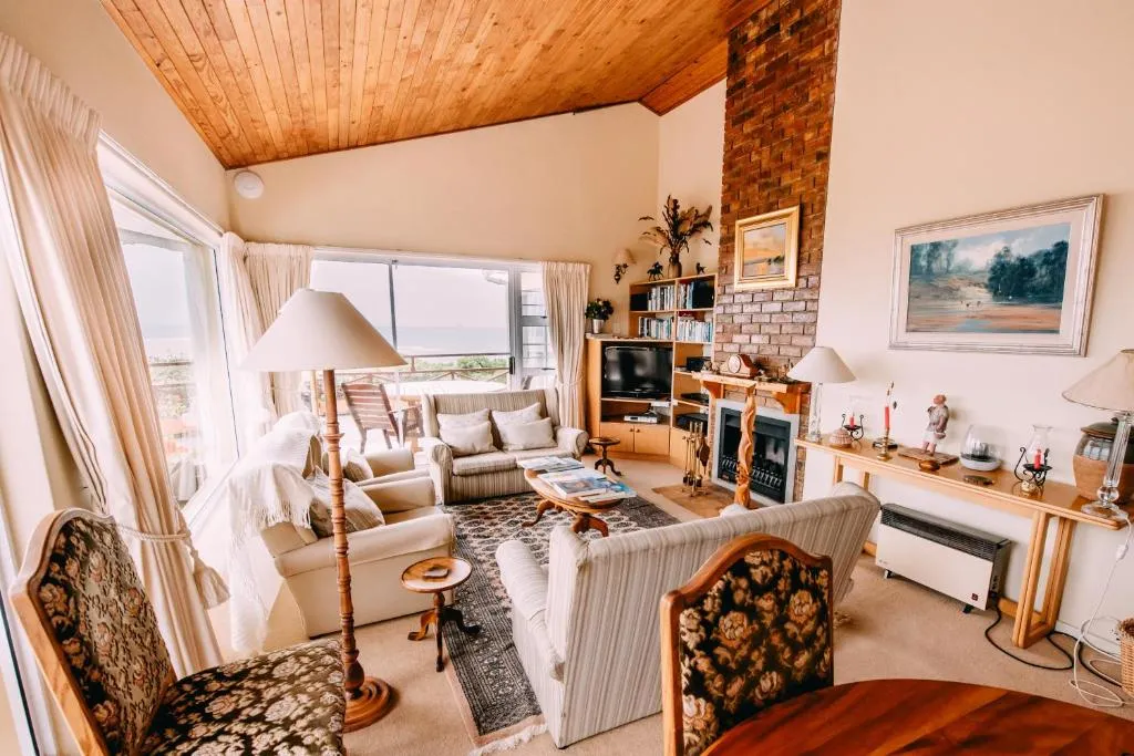 Living room with a brick fireplace, vaulted wood ceiling and sea-facing windows