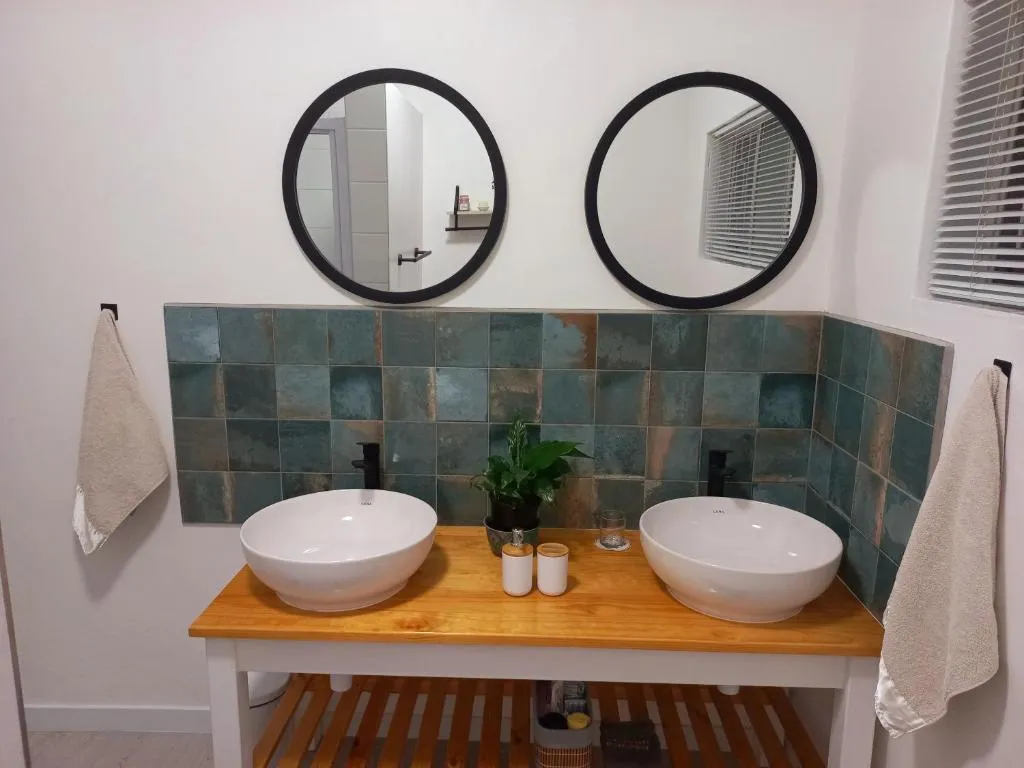 Double vanity with round mirrors, vessel basins and a blue-green patterned tile splashback