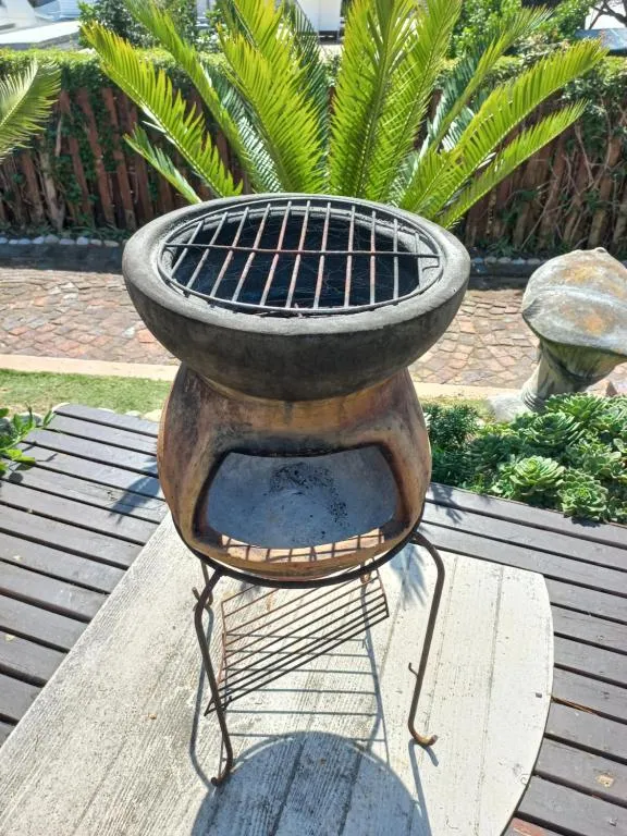 Clay chiminea braai with a wire grill grate on the garden deck