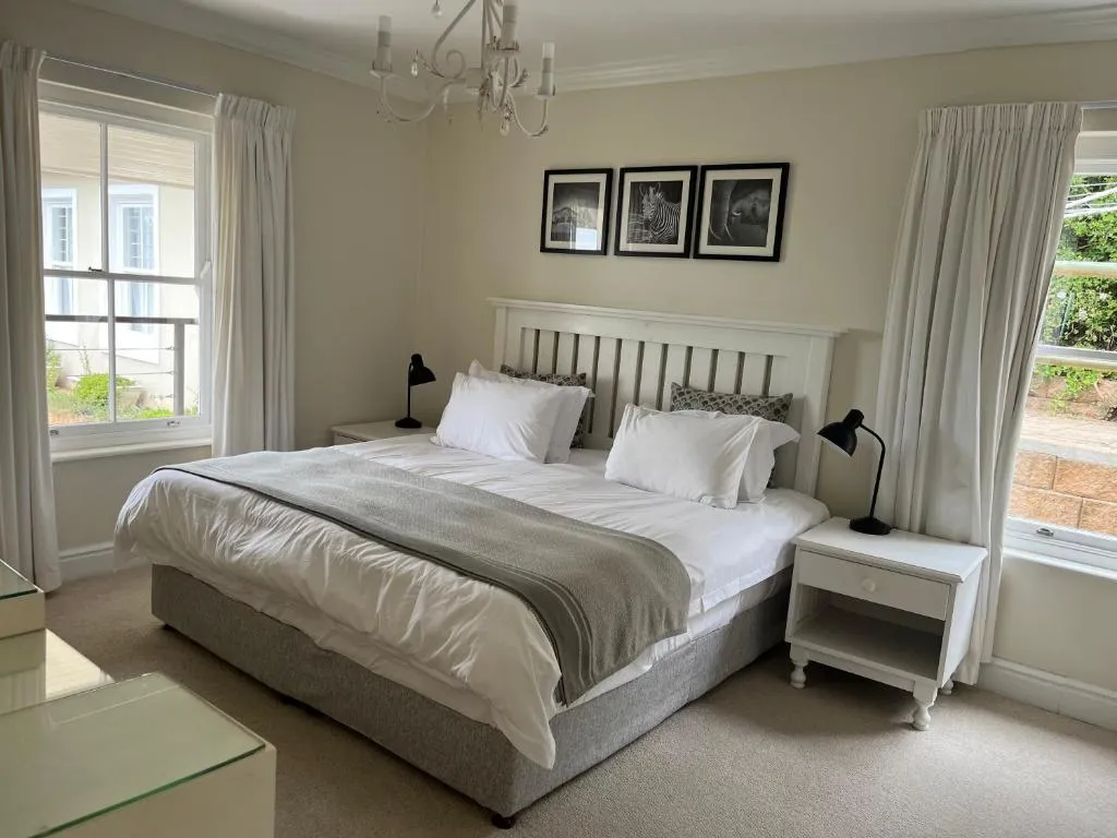 Bedroom with a slatted white headboard, black-and-white wildlife prints, and windows on two sides