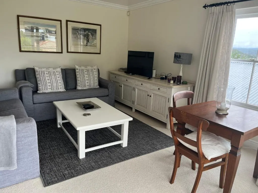 Dining and TV area with a wooden table, a sideboard, and a window looking toward the sea