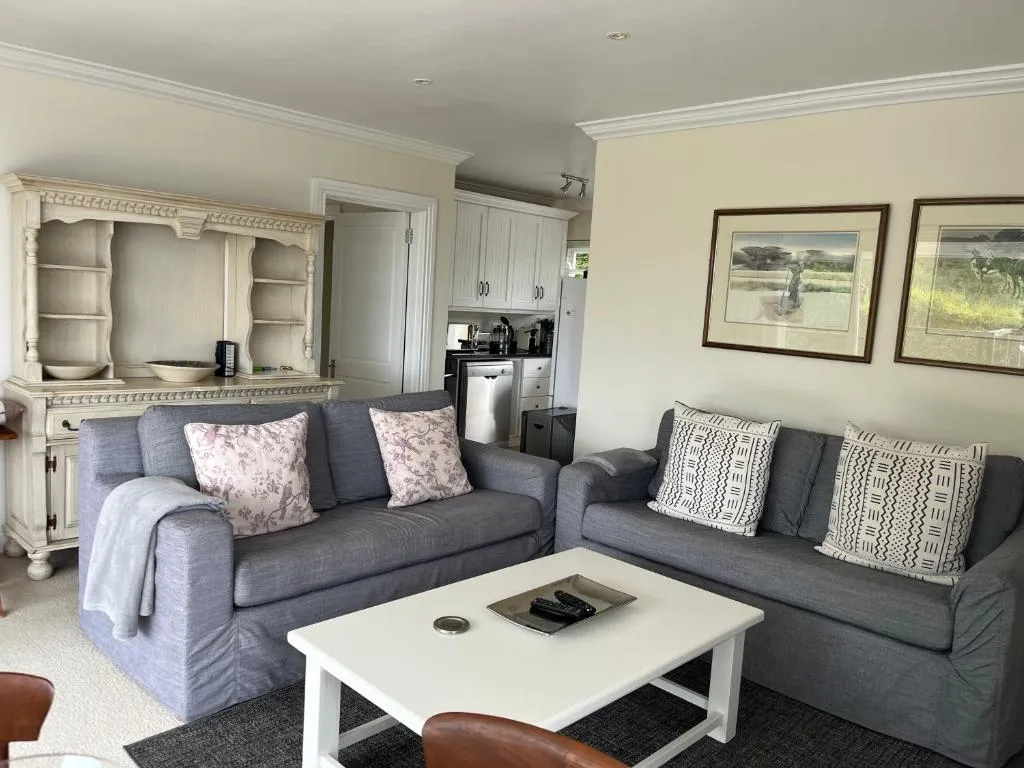 Open-plan lounge with two grey sofas, a cream display hutch, and the kitchen beyond