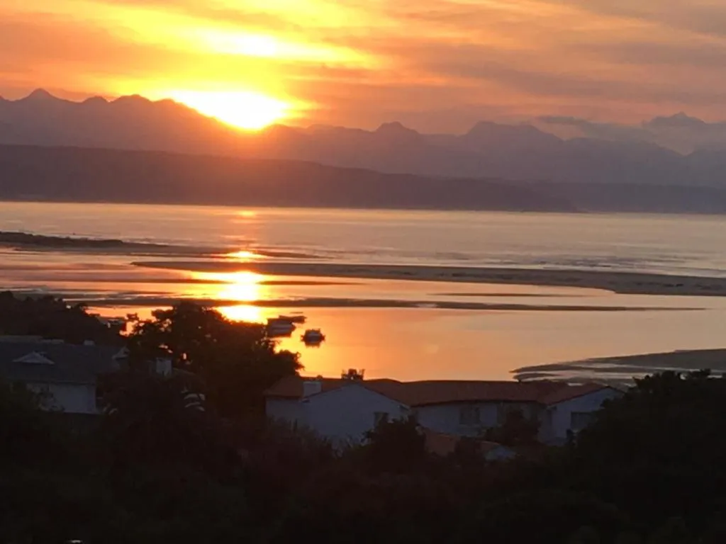Sunset over the lagoon and mountains, silhouetting the rooftops and trees below