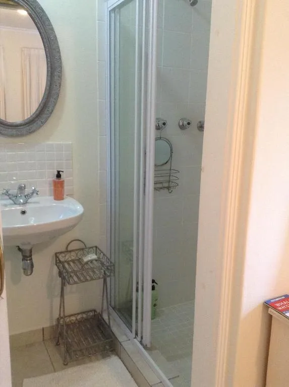 Bathroom with a corner shower, pedestal sink, and an oval mirror