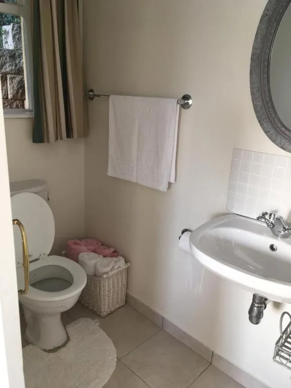 Bathroom with a toilet, towel rail, and a wall-mounted sink beneath an oval mirror