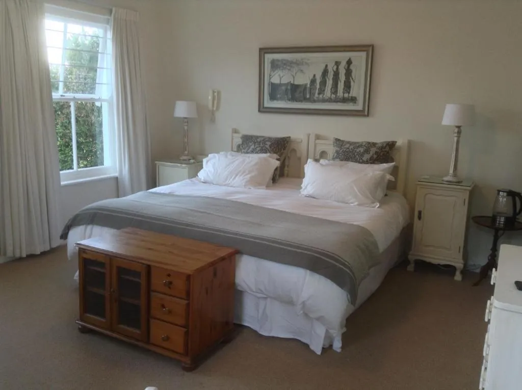 Bedroom with a carved wooden headboard, bedside lamps, and a large sash window