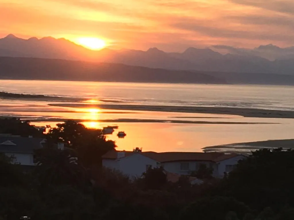 Sunset over the lagoon and mountains, with the shoreline houses silhouetted below