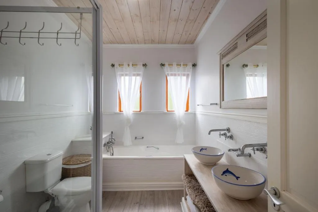 Bathroom with dolphin-patterned vessel sinks, a built-in tub and sheer curtains at the windows