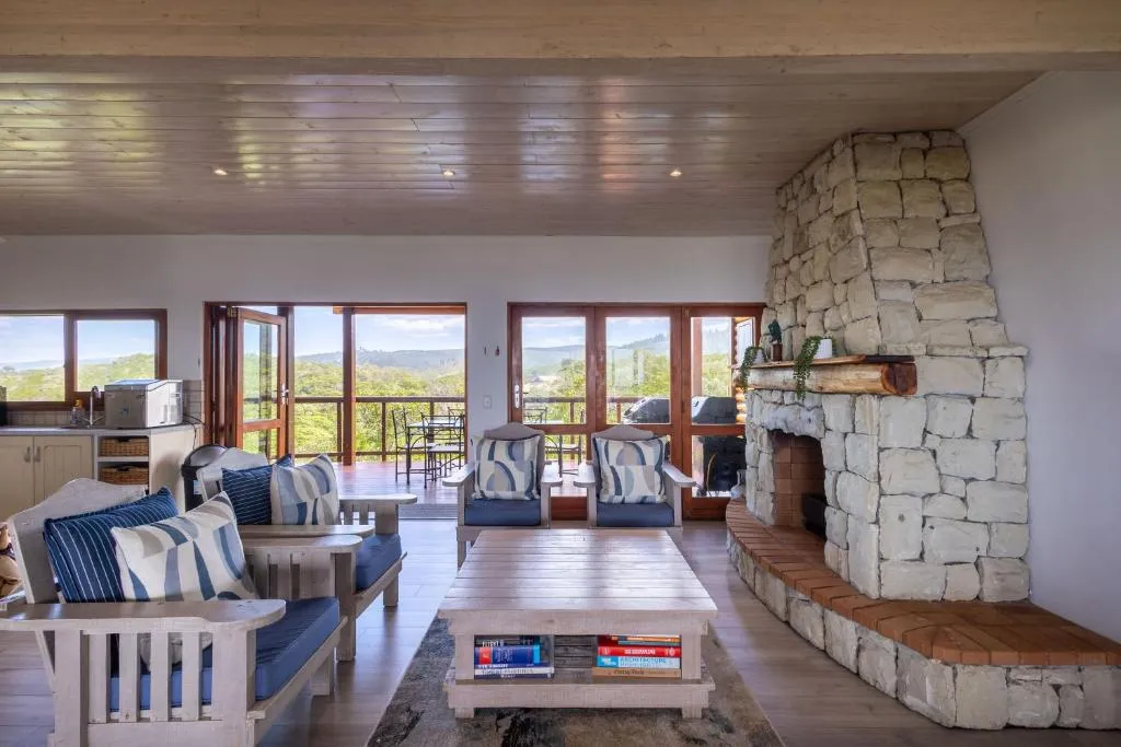 Living room with a floor-to-ceiling stacked-stone fireplace and glass doors onto the deck