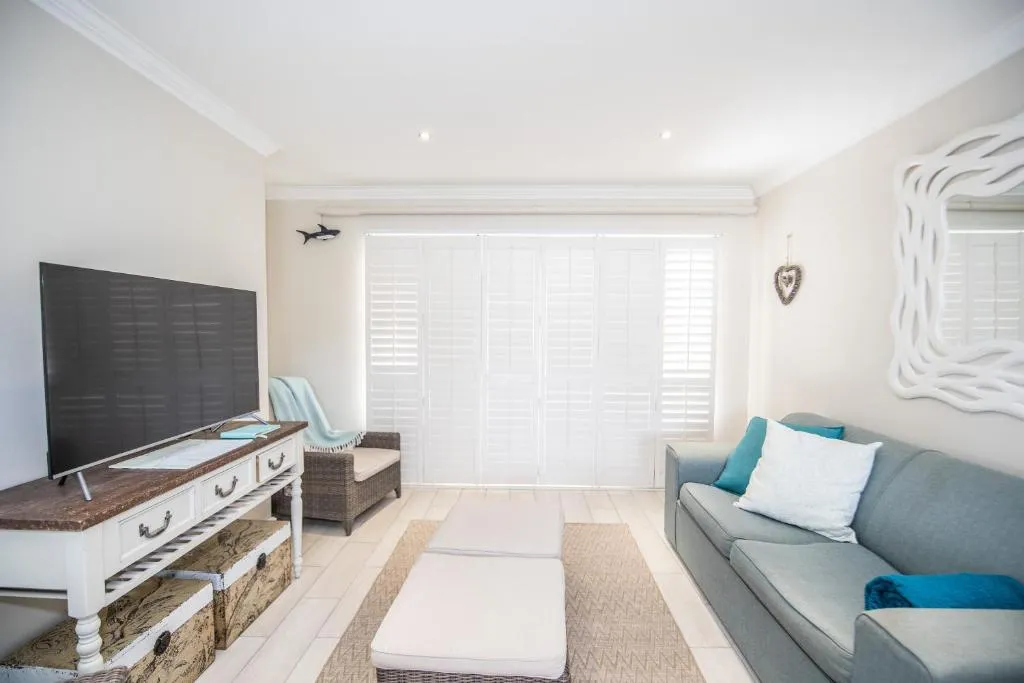 Lounge with grey sofa, wall-mounted TV console and white plantation shutters