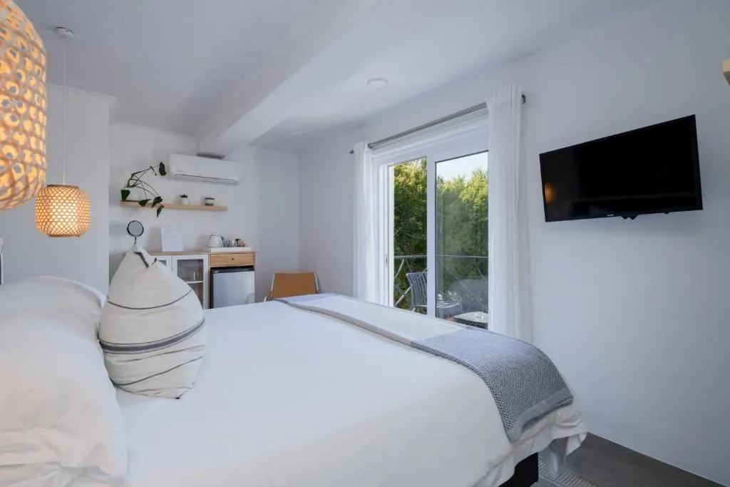 Guest room with sliding doors onto a small balcony screened by greenery