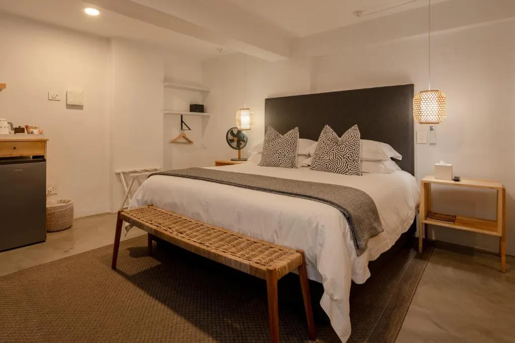 Guest room with a dark upholstered headboard, patterned cushions and pendant lighting