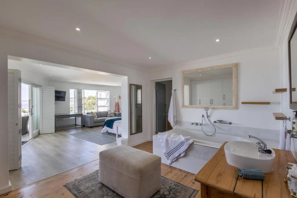 Freestanding bathtub with an ornate mirror, opening through to a sitting area and sea-view door