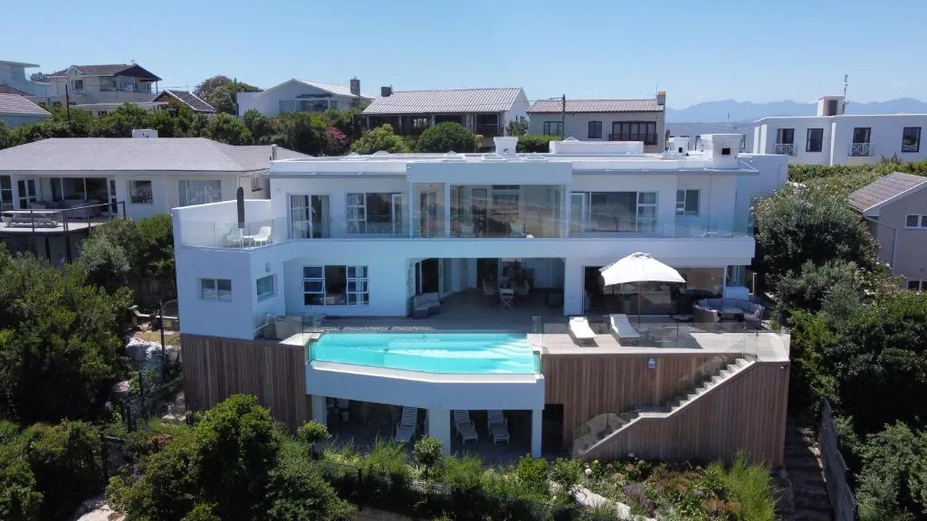Aerial view of the multi-level villa showing the infinity pool, timber decks and glass balustrades